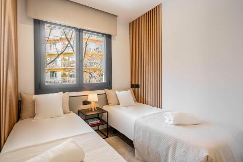 two beds in a room with two windows at ApartsNouBcn Equador Les Corts in Barcelona