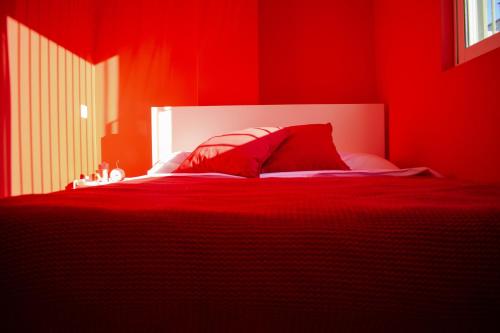 a red bedroom with a bed with red sheets and pillows at RYB Colour Apartment in Patra