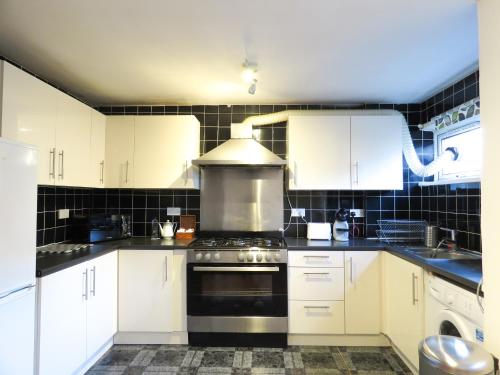 a kitchen with white cabinets and a stove top oven at Tudors eSuites Five Ways Private Terrace & Parking in Birmingham