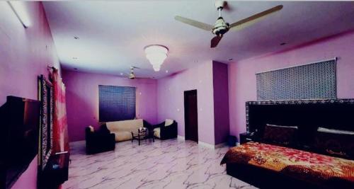 1 dormitorio con paredes moradas, 1 cama y 1 sofá en Best Couple Coprtive Guest House en Karachi