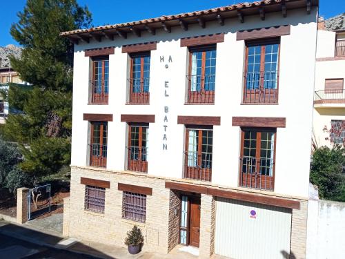 biały budynek z czarnymi oknami w obiekcie apartamentos en Castellote el batan w mieście Castellote