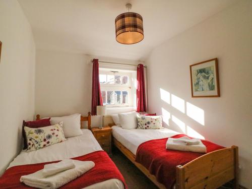 1 dormitorio con 2 camas y ventana en The Oast House en Weymouth