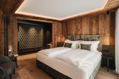 a bedroom with a large bed and wooden walls at Luxury Spa Chalet Lum d'Or in Selva di Val Gardena