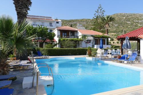 a pool at a hotel with chairs and a building at Jasmine apartments in Pythagoreio