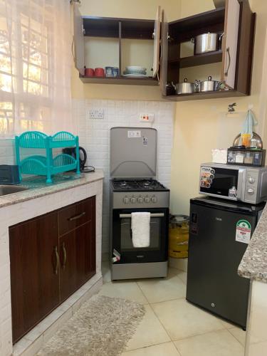 eine Küche mit einem Herd und einer Mikrowelle in der Unterkunft Vee's Homestay, Nakuru Town in Nakuru