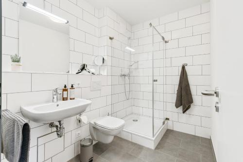 Baño blanco con aseo y lavamanos en Empire Living: Denzlingen Marktplatz, en Denzlingen