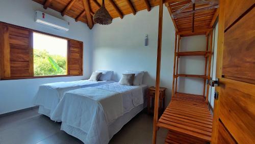 1 dormitorio con 2 camas y ventana en Aldeia Biribiri - Pousada, en Caraíva