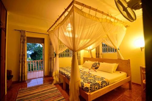 ein Schlafzimmer mit einem Himmelbett und einem Fenster in der Unterkunft Cycad Entebbe Guest House in Entebbe
