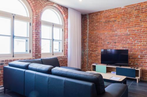a living room with a blue couch and a brick wall at Les Lofts du Trésor - Par Les Lofts Vieux-Québec in Quebec City