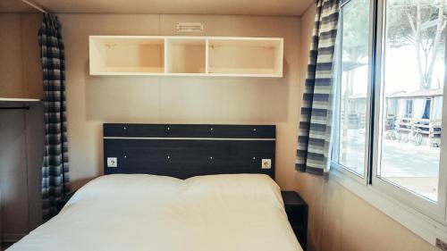 a small bedroom with a bed and a window at Chalet Grand Charme voor 4 personen op Camping River Village - JoyCasa in Ameglia