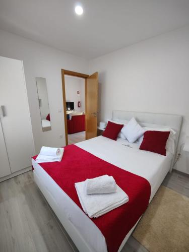 a bedroom with a large white bed with red pillows at Quinta da Alqueidosa - Casa de Campo in Guarda