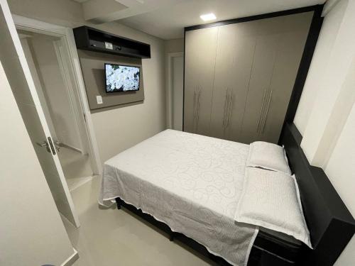 een kleine slaapkamer met een bed en een televisie bij Novo central 2 quartos wifi/garagem/elevador in Foz do Iguaçu