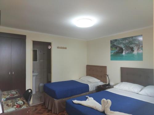 a hotel room with two beds with blue sheets at Bellissa House in Antofagasta