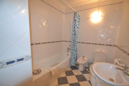 La salle de bains est pourvue d'une baignoire, de toilettes et d'un lavabo. dans l'établissement Ocean Moradia com vista para a vila, à São Martinho do Porto