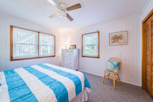 a bedroom with a bed and a chair and windows at Coker Cabana in Sanderling