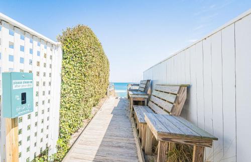 two benches sitting on a sidewalk next to the beach at Coker Cabana in Sanderling