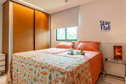 ein Schlafzimmer mit einem Bett mit einer orangefarbenen Tagesdecke in der Unterkunft Apt Marulhos-BeiraMar Praia de Muro Alto-058M in Ipojuca