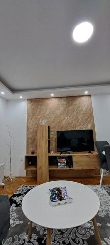 a living room with a white table and a flat screen tv at Apartmani Vranić in Vrdnik