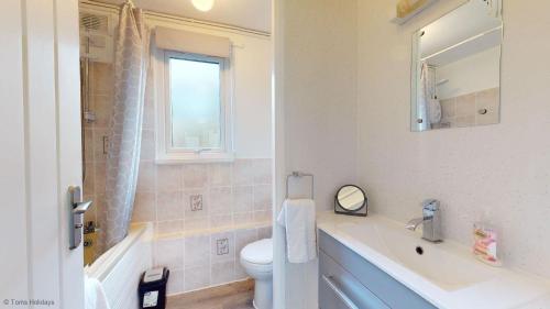 a bathroom with a sink and a toilet and a window at 39 Strawberry Hill, Tolroy Manor in Hayle