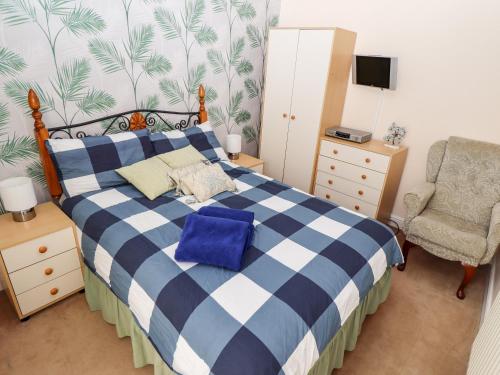a bedroom with a blue and white bed and a chair at Bank House in Mablethorpe