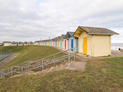 a row of beach huts on a hill next to the ocean at Bank House in Mablethorpe