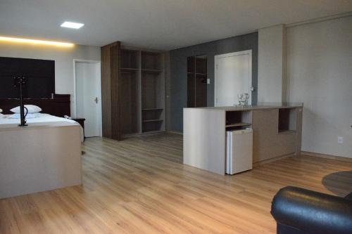 a living room with a bed and a kitchen and a room with a hard wood at Map Hotel in Lages