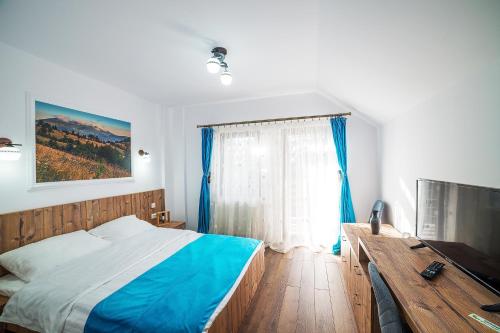 een slaapkamer met een bed, een bureau en een raam bij Drag de Bucovina in Gura Humorului