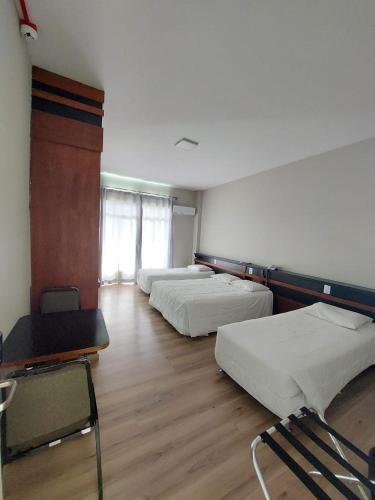a room with three beds and a table and chairs at Map Hotel in Lages