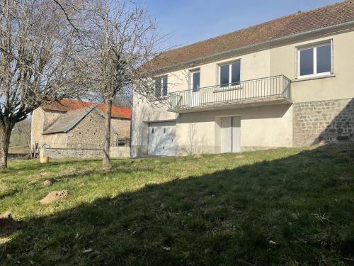 une maison avec une cour herbeuse à côté d'un bâtiment dans l'établissement Gîte des Buis, à Moutier-Rozeille