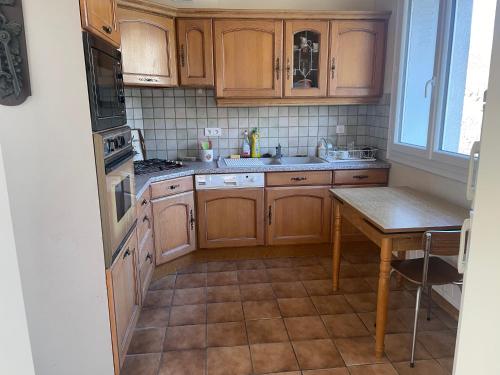 una cocina con armarios de madera y una mesa. en Gîte des Buis, en Moutier-Rozeille