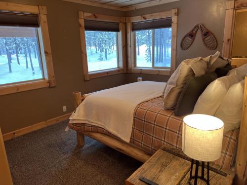 a bedroom with a bed with a table and windows at Lakeside, Hot Tub Theater Room in Island Park