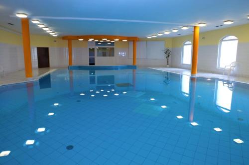 - une grande piscine dotée de carrelage bleu et de fenêtres dans l'établissement Hotel Floret, à Průhonice