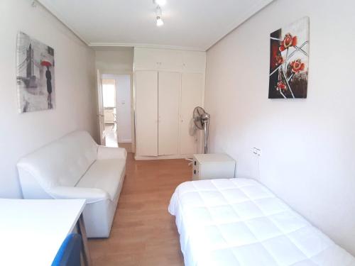 una stanza bianca con un letto e un divano di Apartamento Obispo Frutos a Murcia
