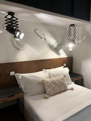 a bedroom with a bed with white sheets and two lights at Valentine's House in Óbidos