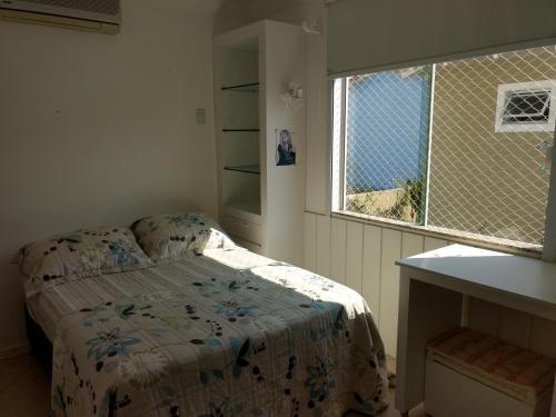 Habitación pequeña con cama y ventana en Linda casa com piscina e 4 suites no mariscal a 100 metros da praia, en Bombinhas