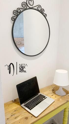 a laptop sitting on a table with a mirror at Hotel Nizza Creative Hotel in Rimini