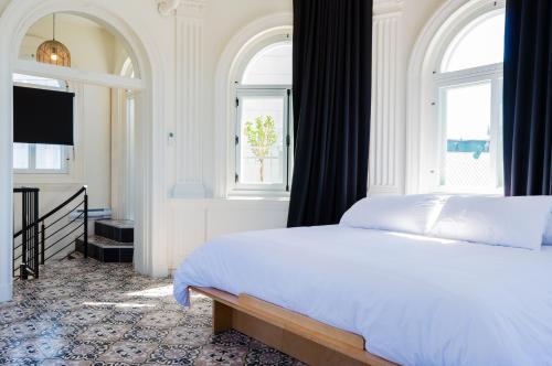 1 dormitorio con 1 cama blanca y 2 ventanas en Les Lofts du Trésor - Par Les Lofts Vieux-Québec, en Quebec