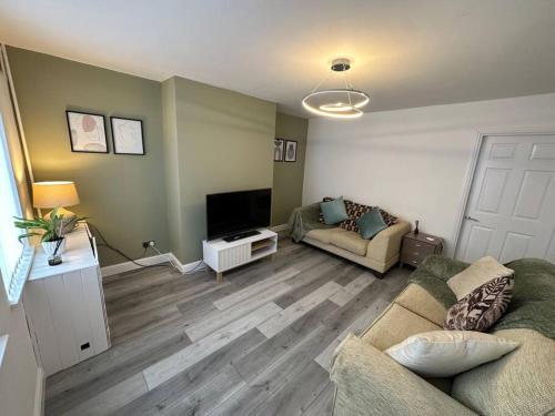a living room with a couch and a tv at MMC Serviced accommodation in Leigh