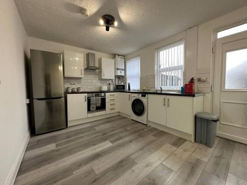 a large kitchen with white appliances and wooden floors at MMC Serviced accommodation in Leigh