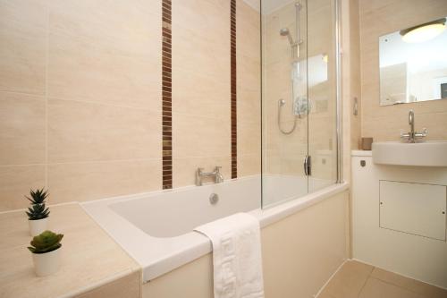 een badkamer met een bad, een douche en een wastafel bij No1 Under the Clock by SSW - Cardiff City Centre in Cardiff