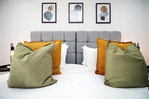 a bed with orange and green pillows on it at No1 Under the Clock by SSW - Cardiff City Centre in Cardiff