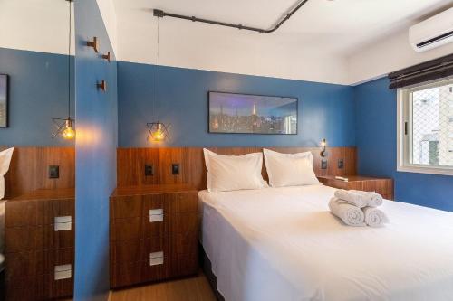 Un dormitorio azul con una cama con toallas. en Apto moderno e decorado perto do metrô Trianon, en São Paulo