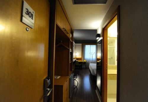 a hallway with a room with a bed and a desk at Bristol Santo André ABC São Paulo in Santo André