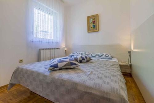 a bedroom with a bed with blue pillows and a window at One-Bedroom Apartment in Crikvenica I in Dramalj