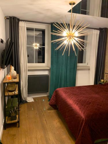 1 dormitorio con cama roja y lámpara de araña en Apartament Gold, en Złotoryja