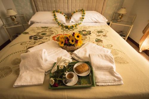 B&B La Dimora delle Calendule في Virgilio: طاولة مع صينية من الطعام والزهور على سرير