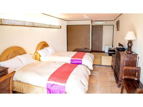 ein Hotelzimmer mit 2 Betten und einem Schreibtisch in der Unterkunft Hachijojima Hotel Resort Sea Pillows - Vacation STAY 53193v in Mitsune