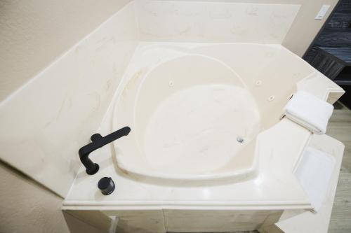 a white toilet with a black handle on it at Sapphire Inn & Suites in Channelview