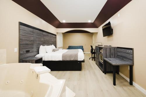 a hotel room with a bed and a tub and a sink at Sapphire Inn & Suites in Channelview