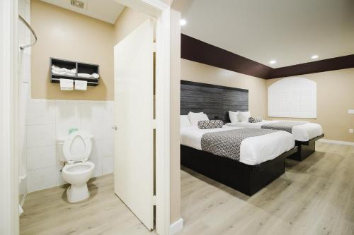 ein Hotelzimmer mit einem Bett und einem WC in der Unterkunft Sapphire Inn & Suites in Channelview